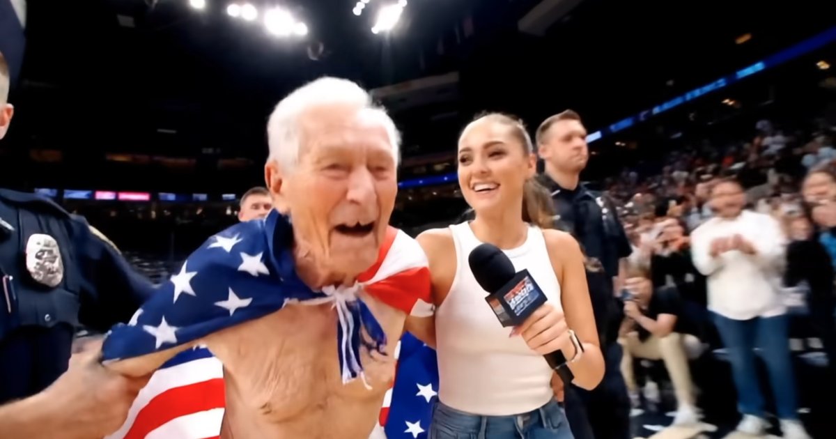 A frame from the AI-generated Kalshi NBA Finals ad: an elderly man draped in an American flag laughs courtside next to a smiling interviewer holding a microphone.